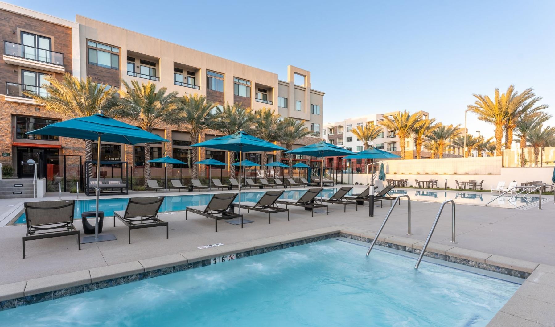 a pool with chairs and umbrellas by a building