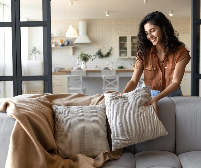 woman putting soft pillows over her couch